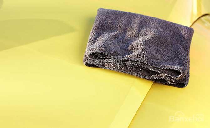 Xịt dung dịch lên khăn để làm sạch xe ô tô
